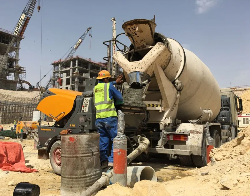 Worker preparing shotcrete beside a concrete mixer at a construction site