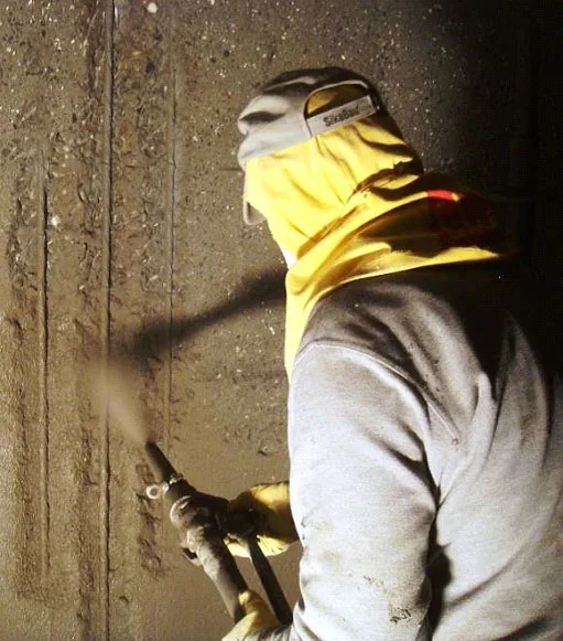 Operator spraying shotcrete onto a concrete surface