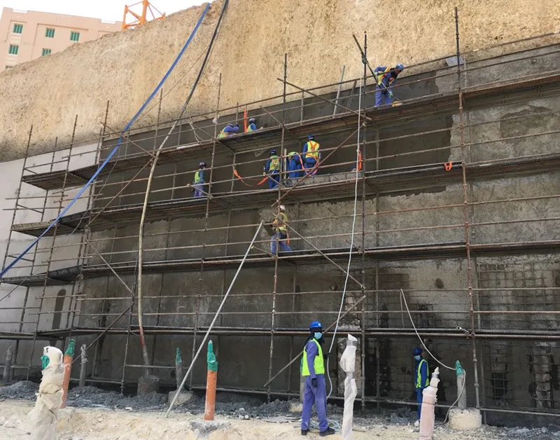 Shotcrete crew working across a scaffolded retaining wall